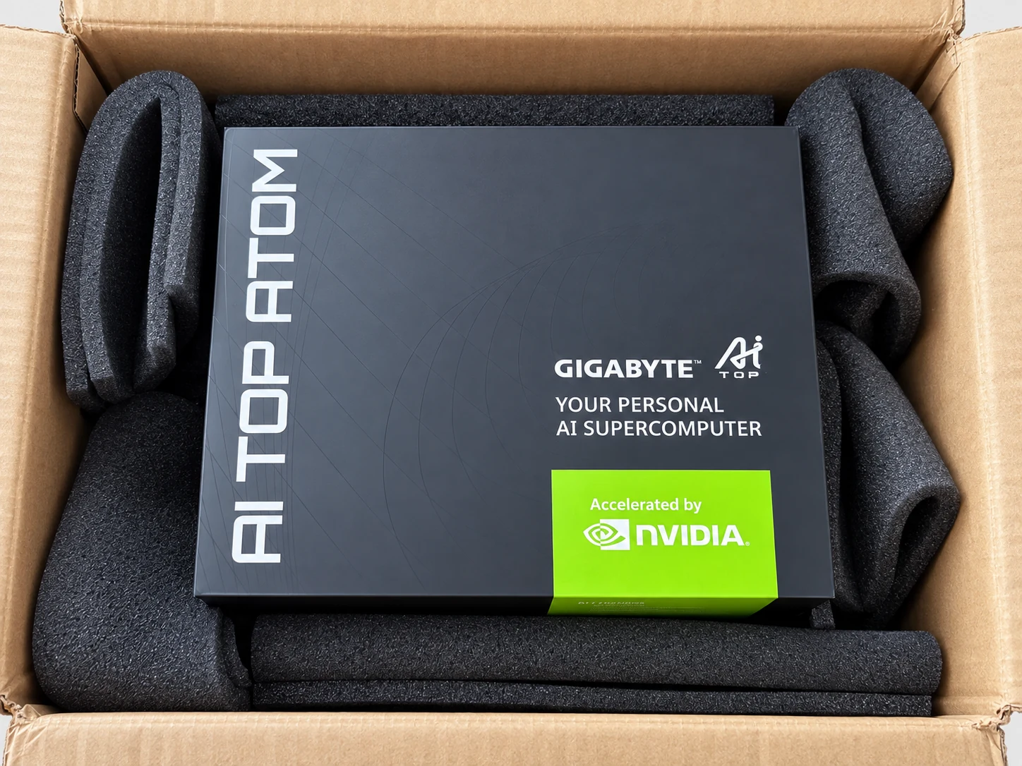 Caja negra de la AI TOP ATOM en su embalaje de envío, asegurada con espuma, con las menciones GIGABYTE AI TOP y Accelerated by NVIDIA.