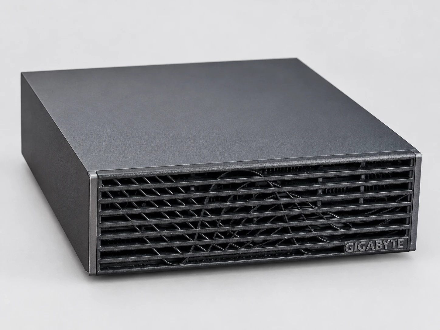 La AI TOP ATOM de GIGABYTE vista en tres cuartos desde el lado derecho, colocada en horizontal: cubierta gris antracita y frontal de lamas negras.