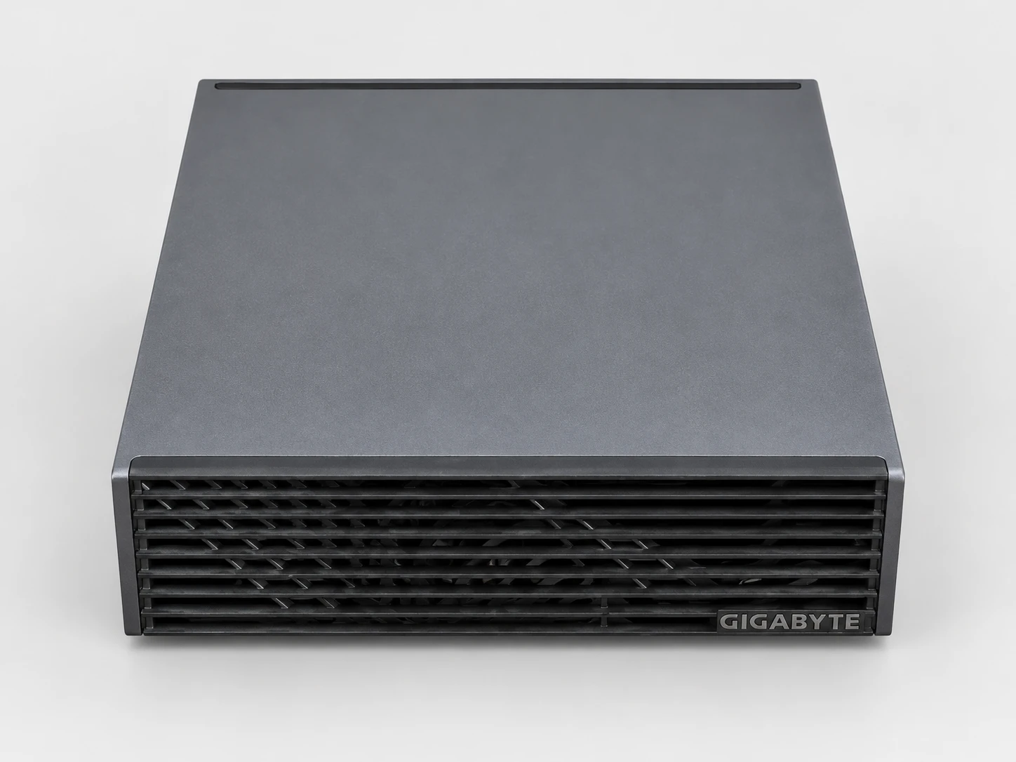 La AI TOP ATOM vista desde arriba y de frente: tapa lisa gris antracita, frontal con lamas y logotipo de GIGABYTE.
